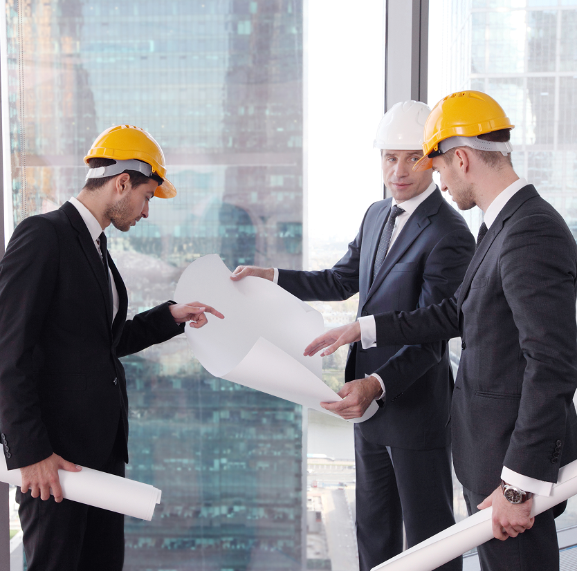 Three engineers discussing building plans indoors. Three engineers discussing building plans indoors.