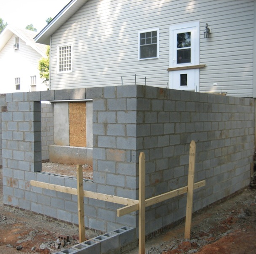 Cinder block extension under construction beside house.