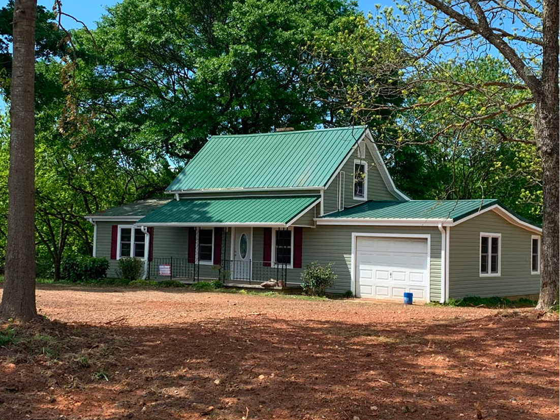 House with green roof and trees outside.